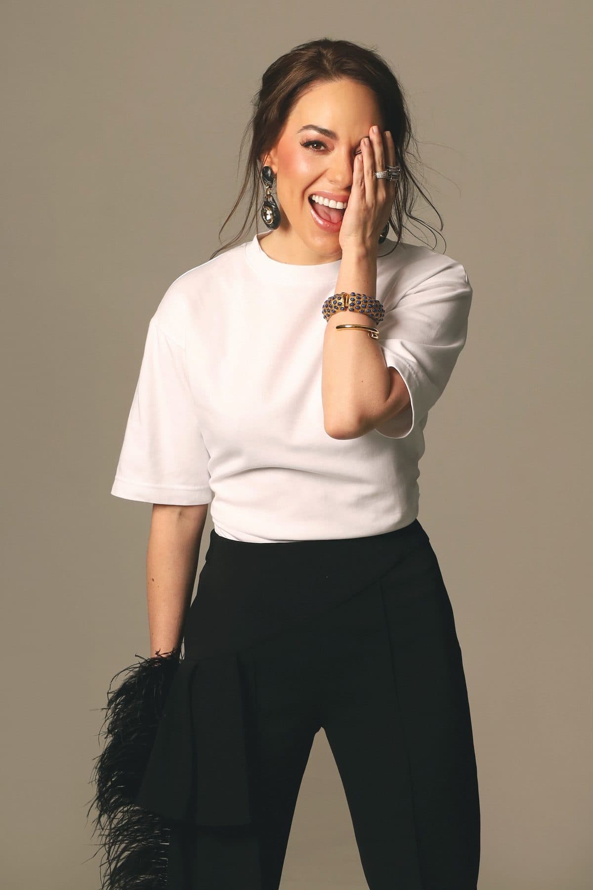 Cordelia ríe, sentada en el suelo con camiseta blanca y pantalón negro.
